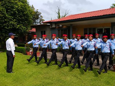 Security guards performing drill training in red berets at company premises